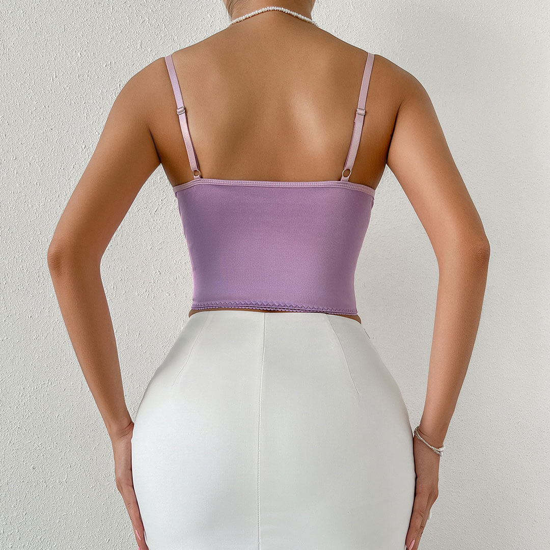back view of a woman wearing a purple satin corset top and a white skirt