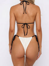 Woman wearing a cream and black string bikini from the back