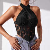 Woman wearing a black halter neck lace and mesh corset top with blue jeans.