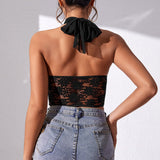 Back view of a woman wearing a black halter neck lace and mesh corset top with blue jeans.