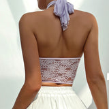 Back view of a woman wearing a white lace halter crop top.