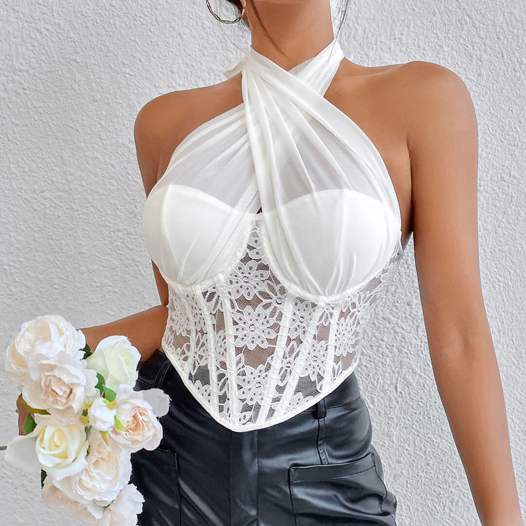 Woman wearing a white lace corset top with a halter neck and black pants, holding a bouquet of white roses.