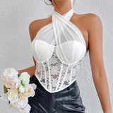 Woman wearing a white lace corset top with a halter neck and black pants, holding a bouquet of white roses.