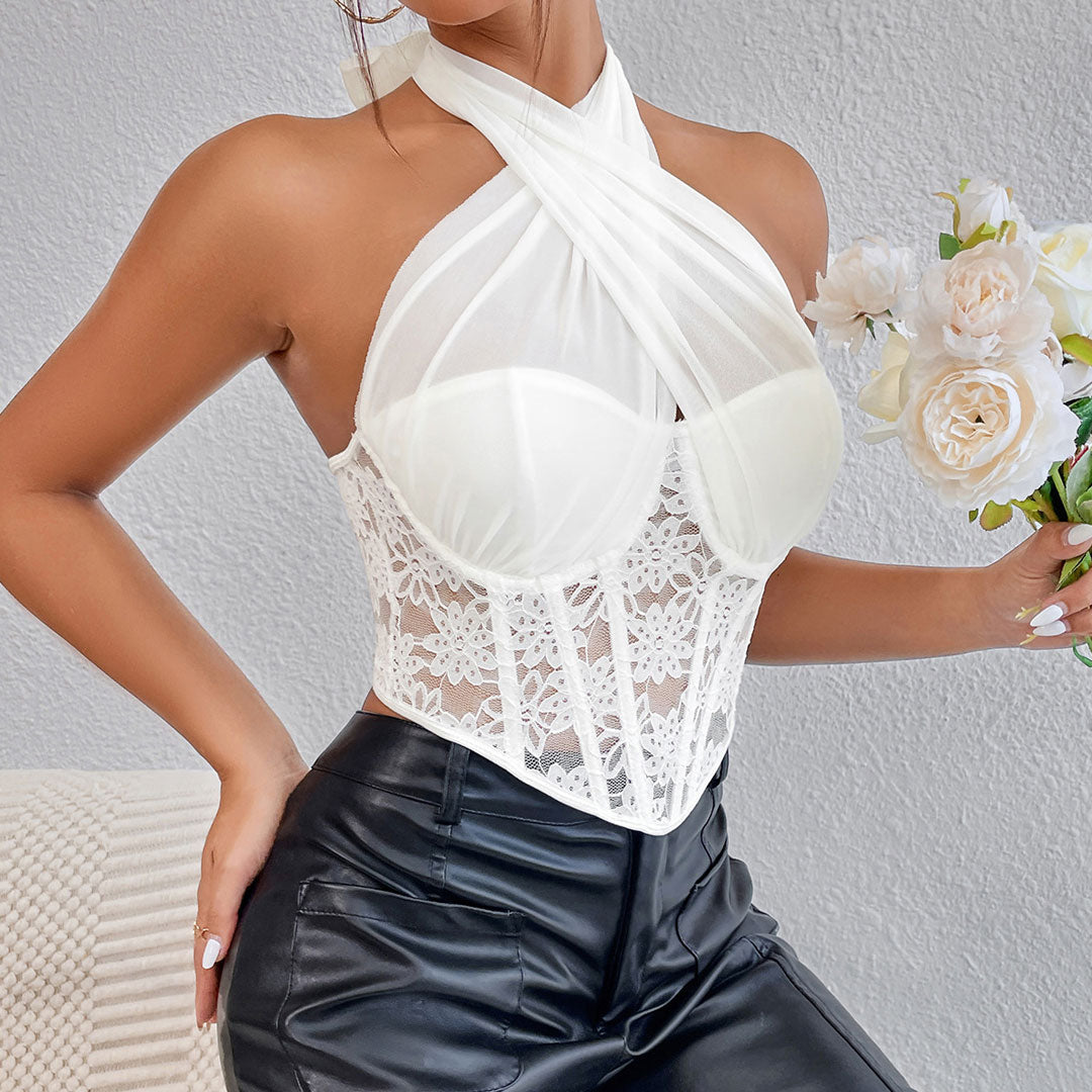 Close-up of a woman wearing a white lace corset top with a halter neck and black pants, holding a bouquet of white roses.