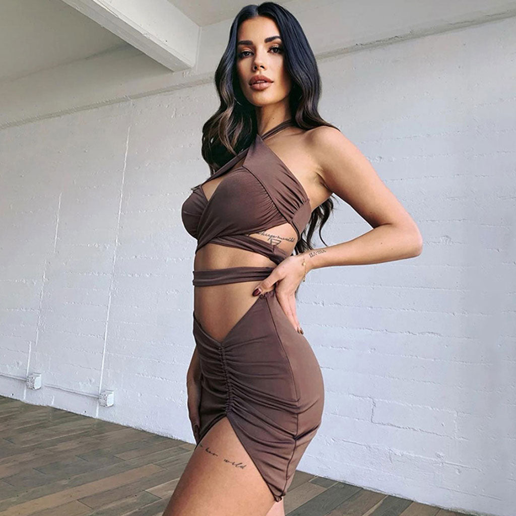 Side view of a woman in a brown halter neck two-piece dress with cut-out details and a ruched skirt.