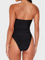 Rear view of a woman wearing a black strapless one-piece swimsuit.