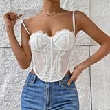 A woman wearing a white lace corset top and blue jeans, with her hand on her hip.