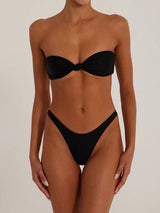 A woman wearing a black strapless bikini with a knotted bust and high-cut bottoms, front view.