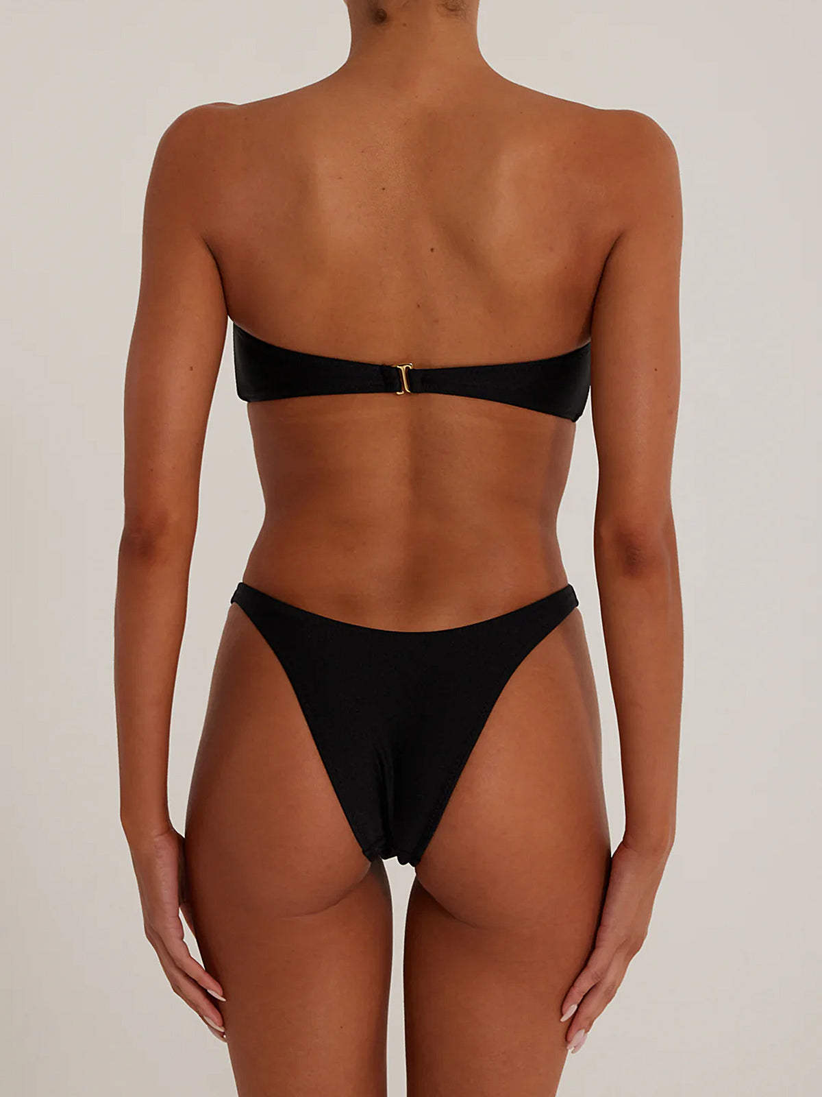 A woman wearing a black strapless bikini with a knotted bust and high-cut bottoms, back view.