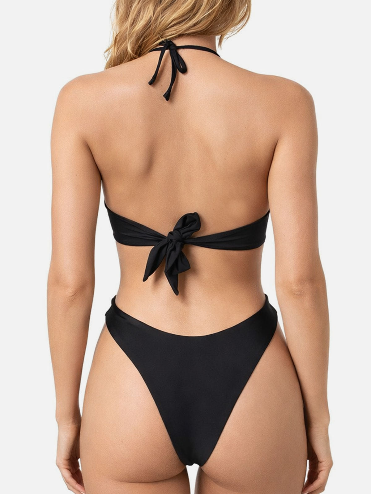 Back view of a woman in a black bikini top tied at the back and high-cut bikini bottoms.