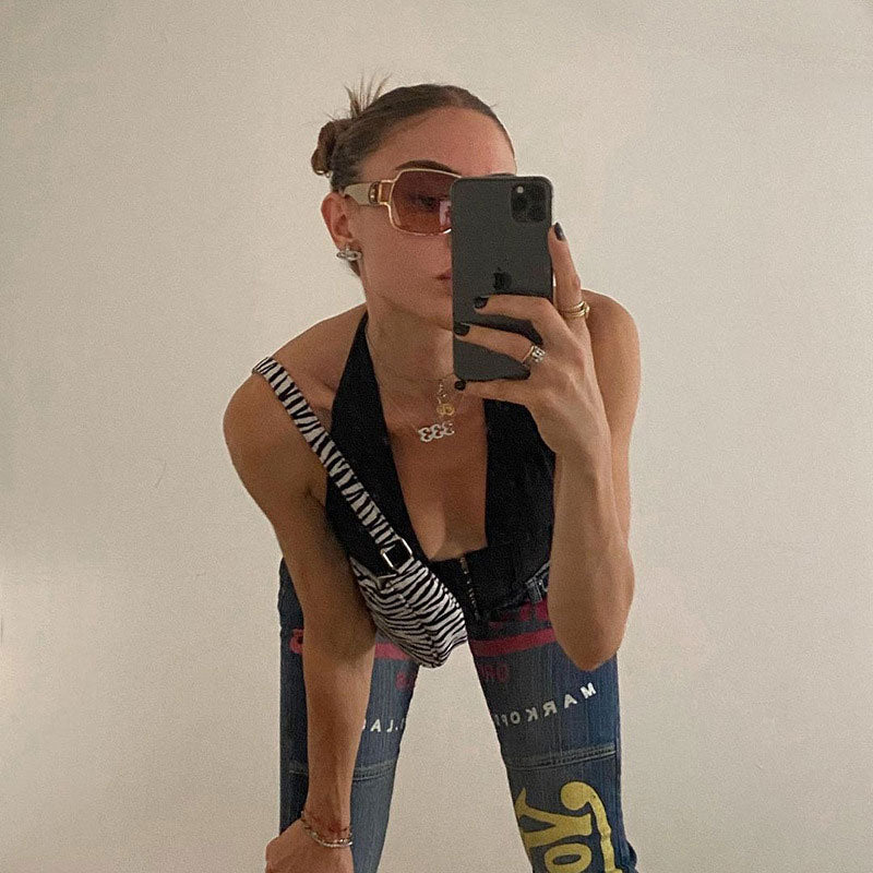 woman in a black halter corset top and jeans taking a selfie