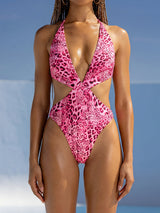Woman wearing a pink leopard print one-piece swimsuit with cut-outs and a plunging neckline