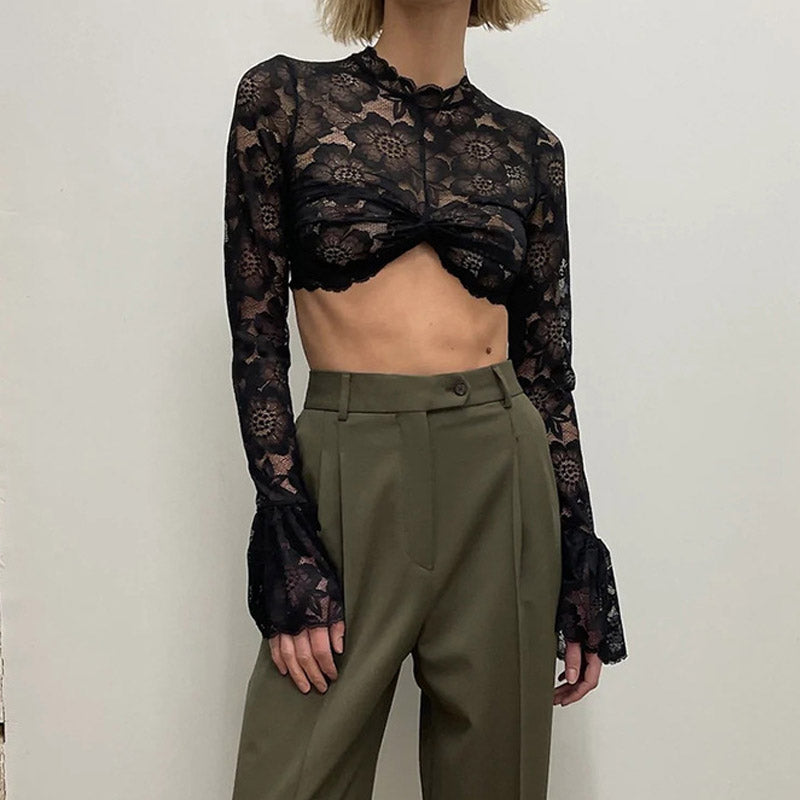 woman wearing a black lace crop top with bell sleeves and olive green high-waisted pants