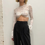 woman wearing a white lace crop top and black high-waisted pants