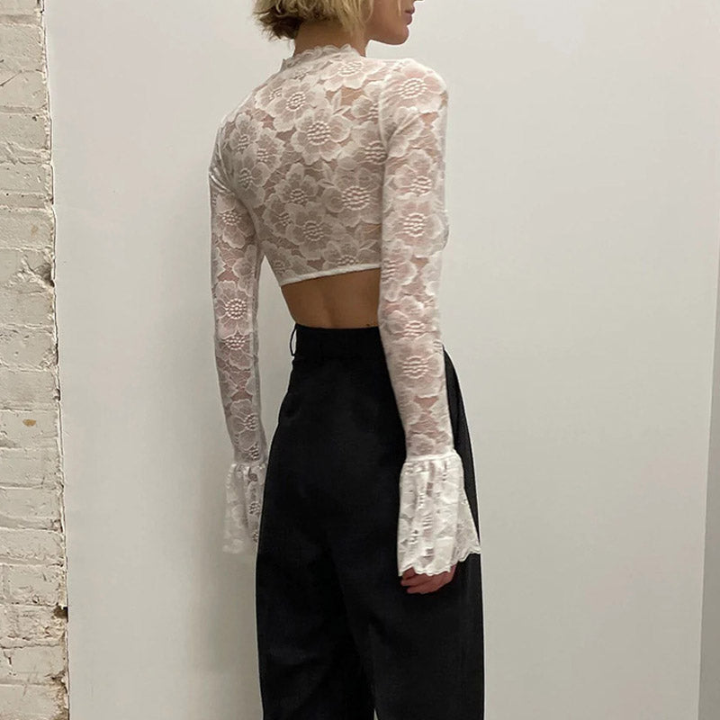 back view of a woman in a white lace crop top and black pants