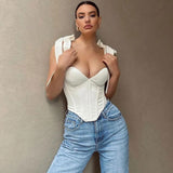 A woman in a white corset top and blue jeans