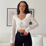 Woman wearing a white lace crop top with long sleeves and black pants