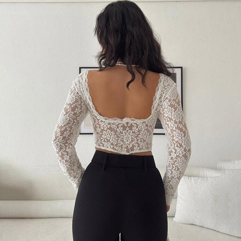 Back view of a woman wearing a white lace crop top with long sleeves and black pants