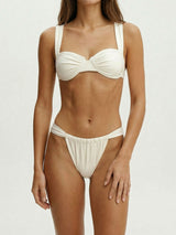 Woman wearing a white bikini with a ruched bust and wide straps, front view