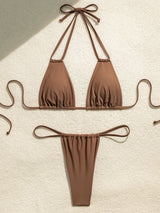 Brown bikini laid out flat on a textured surface.