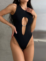 Woman wearing a black one-piece swimsuit with a front cutout and rhinestone embellishment