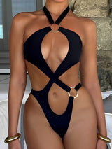Woman in a black one-piece swimsuit with gold ring accents and cut-out details.