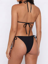Back view of a woman wearing a black ribbed knit halter neck triangle bikini top with a tie back and a matching string bikini bottom with tie sides.