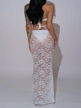 Back view of a woman wearing a white bikini with a white lace maxi skirt