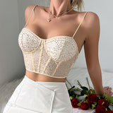 Woman wearing a beige sequined corset top with spaghetti straps and a white skirt, with red roses on the side.