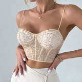 Close-up of a woman wearing a beige sequined corset top with spaghetti straps, a gold necklace, and rings.