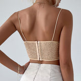 Back view of a woman wearing a beige sequined corset top with spaghetti straps and a zipper closure, paired with a white skirt.