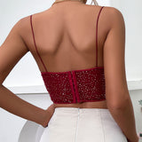 Back view of a woman wearing a red sequined crop top with thin spaghetti straps and a zipper closure at the back.