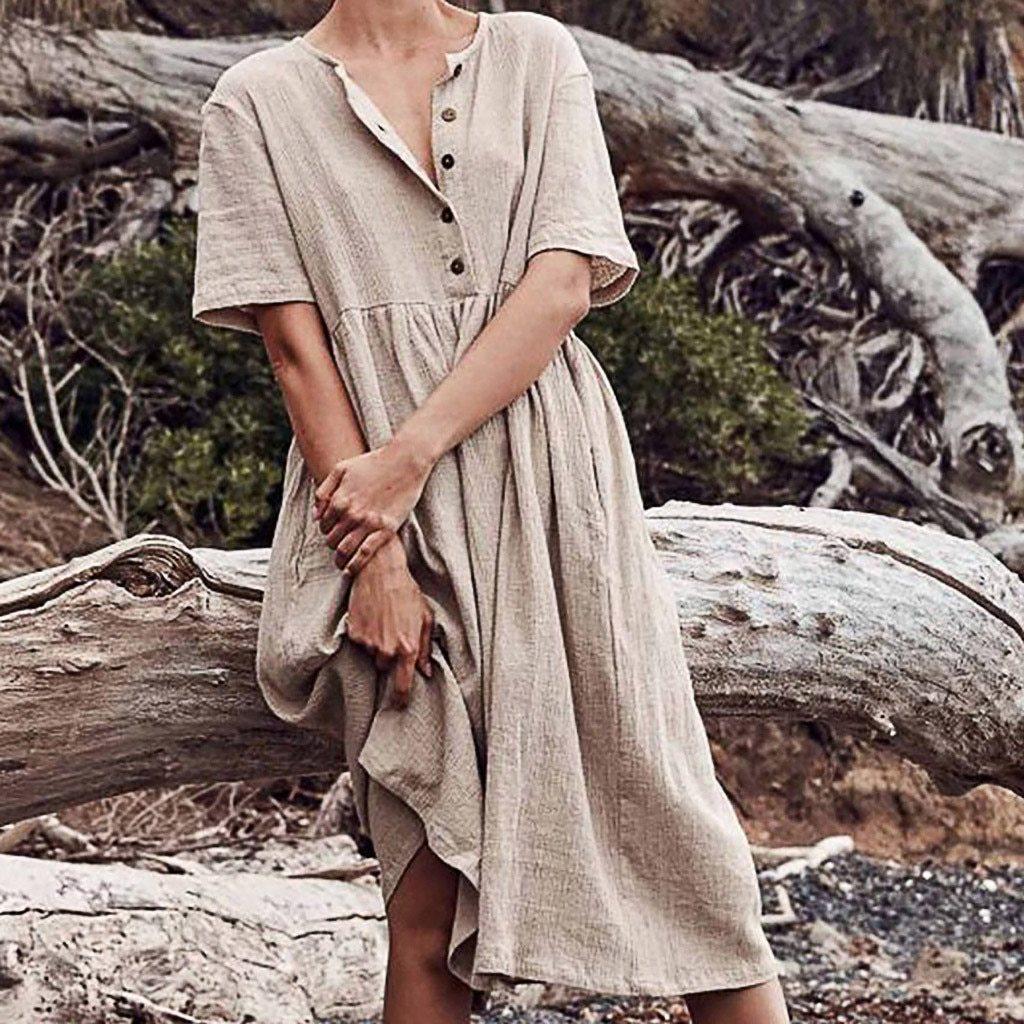 Woman leaning against a log wearing a beige linen dress