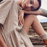 Close-up of a woman's face and shoulder wearing a beige linen dress