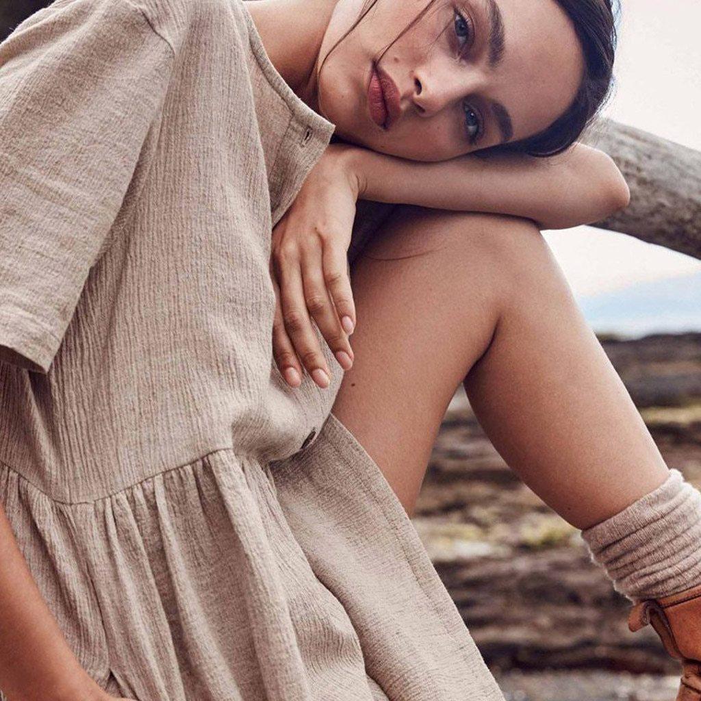 Close-up of a woman's face and shoulder wearing a beige linen dress
