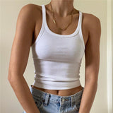 A person wearing a white ribbed tank top and blue jeans.