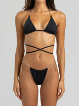 Woman wearing a black bikini with gold chain accents