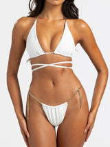 Woman wearing a white bikini with gold chain accents