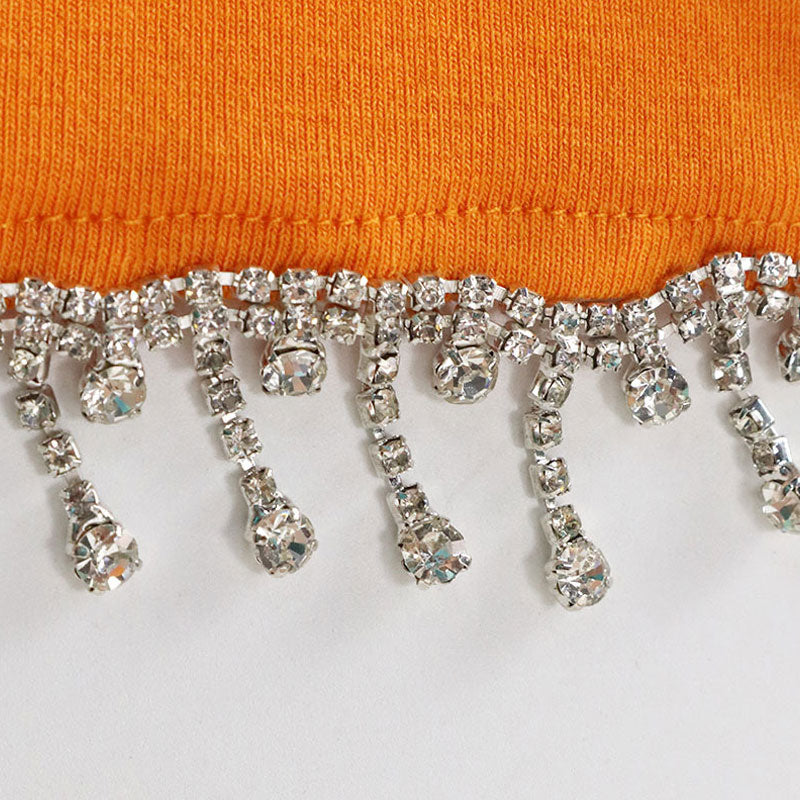 close-up of orange fabric with rhinestone and tassel trim