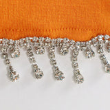 close-up of orange fabric with rhinestone and tassel trim