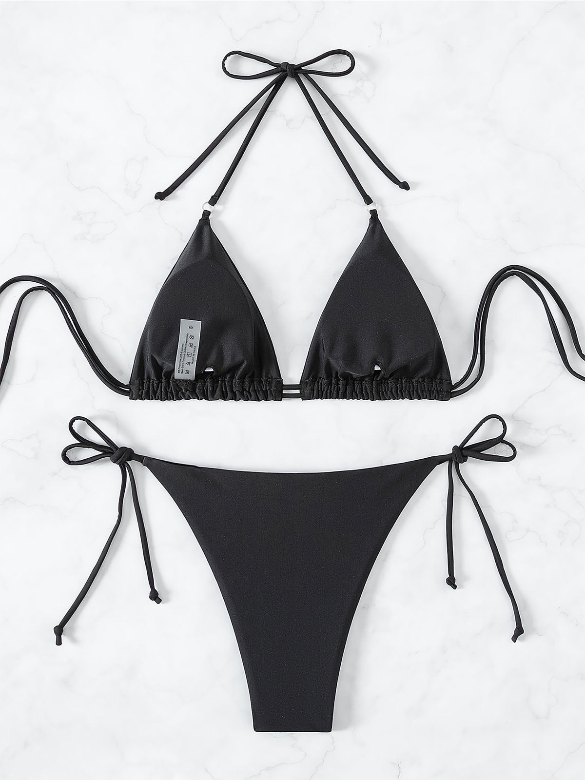 Back view of a black bikini top and bottom laid flat