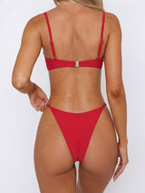 Back view of a woman in a red bikini, showing the adjustable straps and high-cut leg.
