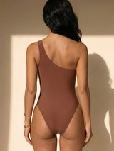 Back view of a woman in a brown one-shoulder swimsuit