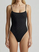 woman wearing a black one-piece swimsuit with white polka dot studding