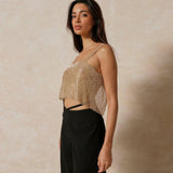 A woman in a gold sequined crop top and black wide-leg pants.
