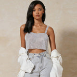 A woman in a silver sequined cropped top and light blue jeans