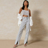 A woman poses in a silver sequined crop top and light blue split hem jeans