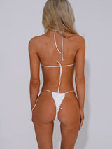 Back view of a woman in a white textured triangle bikini with string tie closures.
