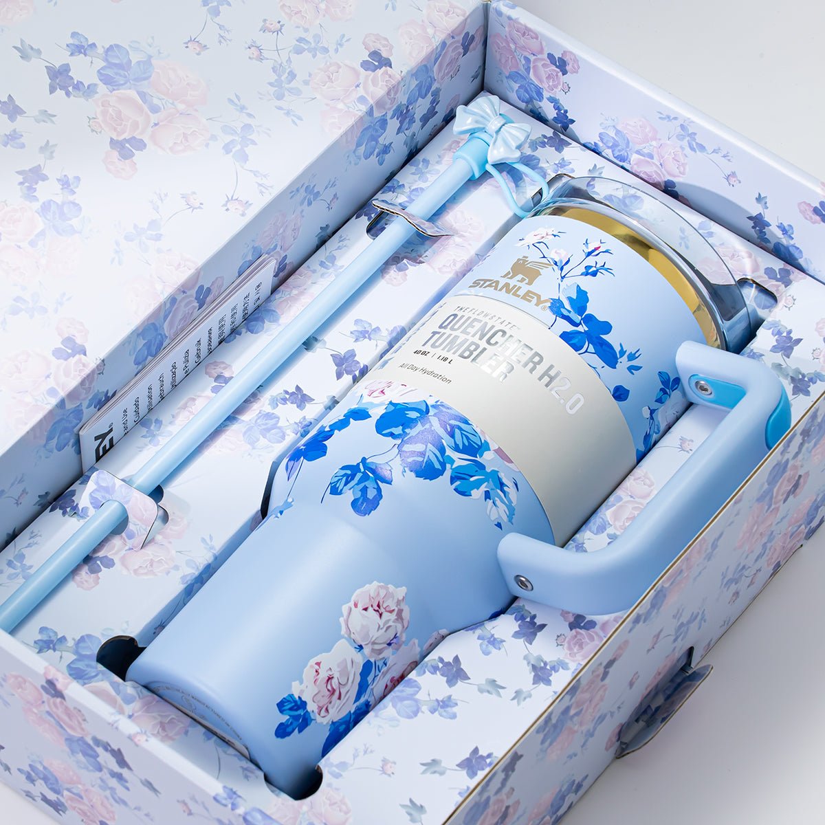 The light blue Stanley Quencher H2.0 Tumbler nestled inside its floral-patterned gift box, complete with a straw and bow accent.