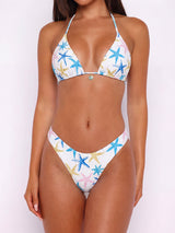 Front view of a woman wearing a white bikini with a blue, pink, and yellow starfish print.